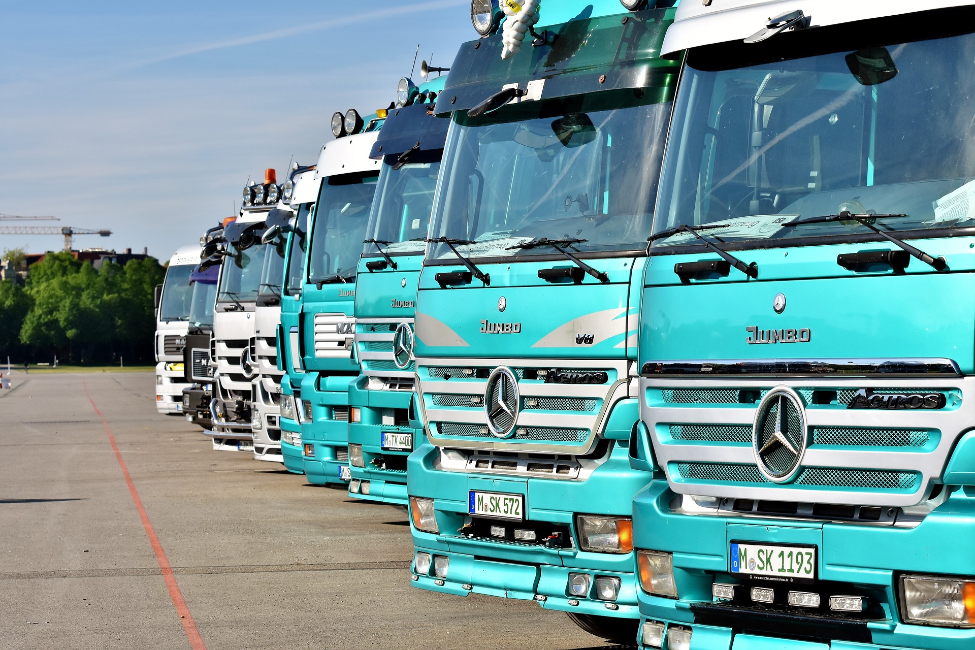 Flota de camiones de color azul cielo estacionados en línea.