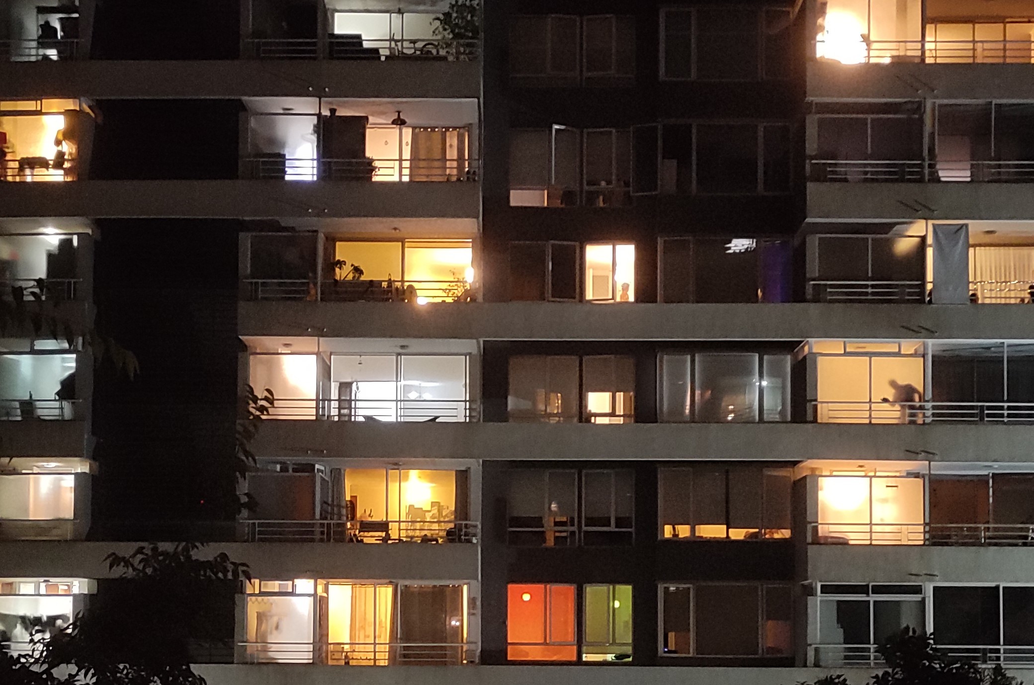 Fachada de un edificio con balcones en medio de la noche con las luces encendidas y apagadas.
