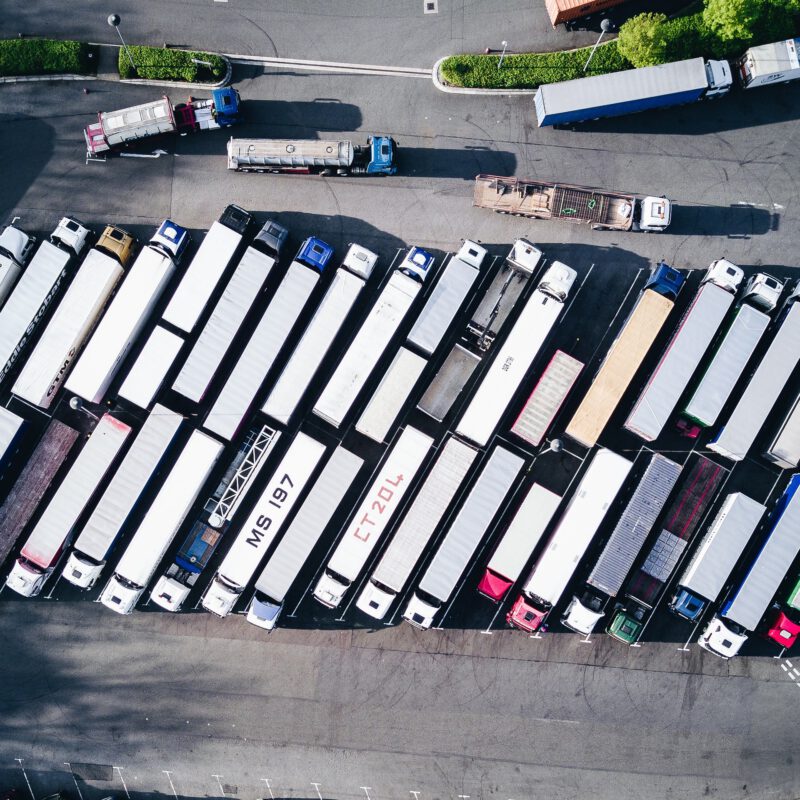 ¿Necesitas un seguro para tu flota de vehículos? Vista desde el aire de un conjunto de camiones aparcados en batería en un área de servicio.