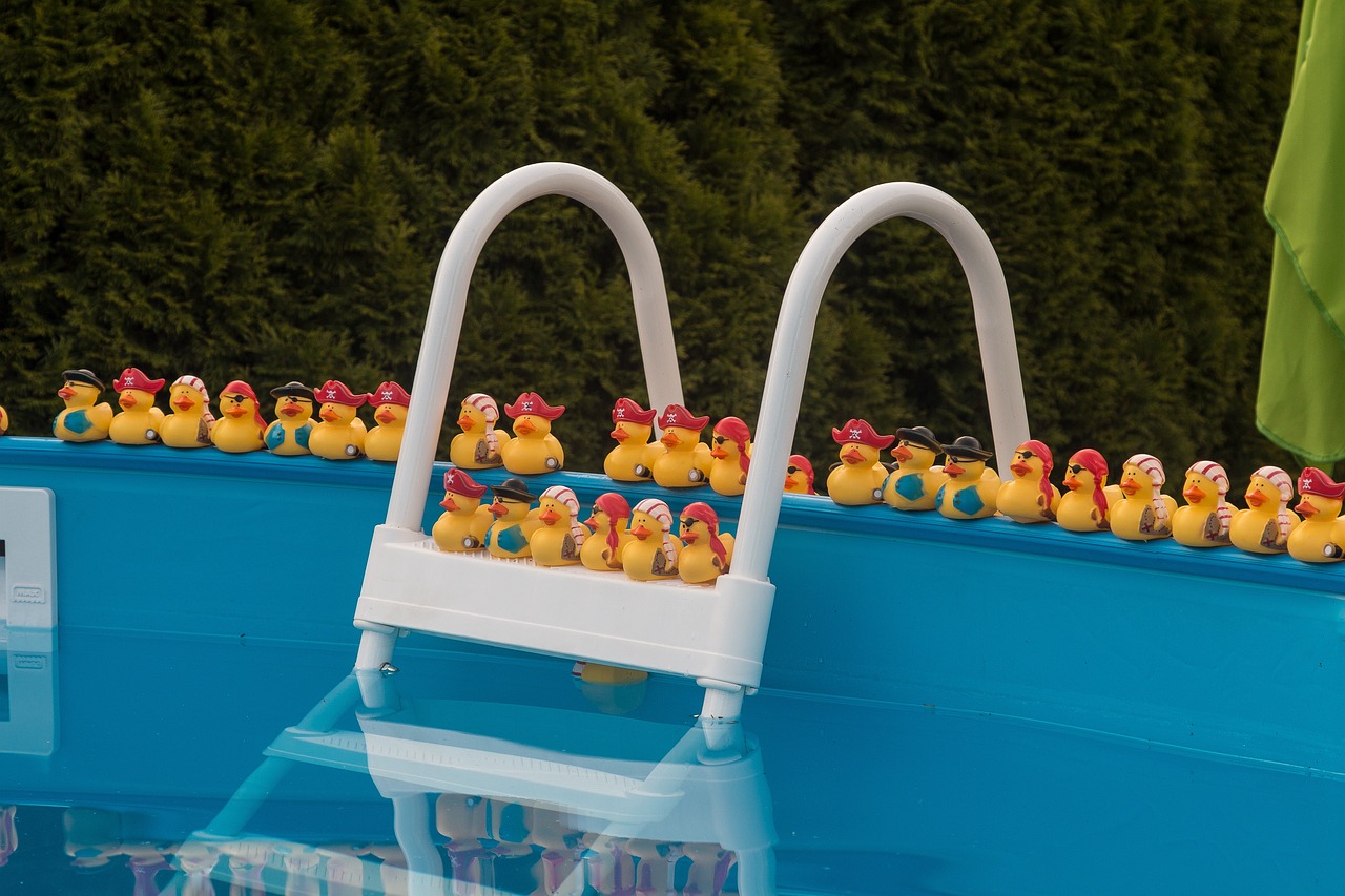 Un ejército de patos amarillos de juguete esperan ansiosos al borde de una piscina de barrio para zambullirse. Seguro de responsabilidad civil para piscinas de comunidades.