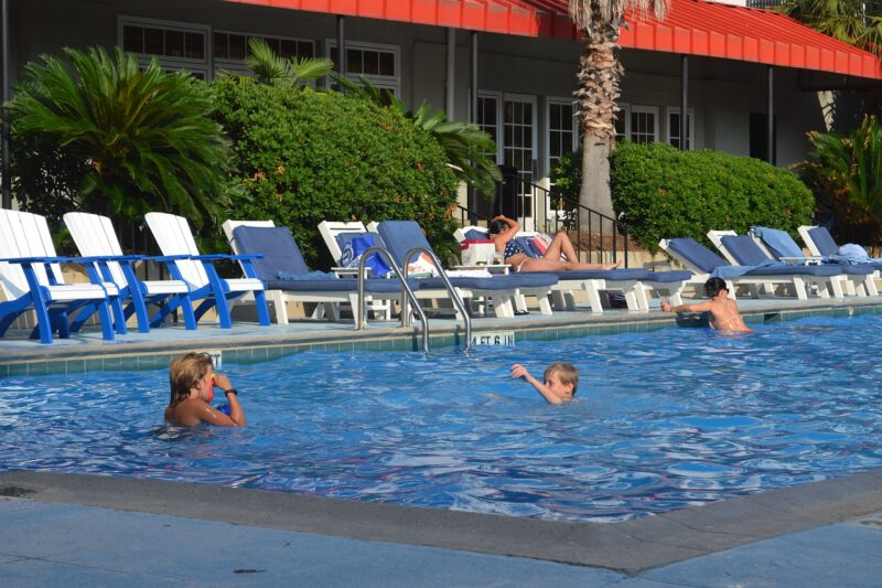 Piscina de una comunidad de propietarios o municipal con dos niños jugando en el agua. Seguro de responsabilidad civil para piscinas.
