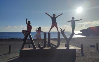 Cuatro niños subidos en las letras de Ajuy en la puesta de sol. Una de las playas más paradisiacas de Fuerteventura