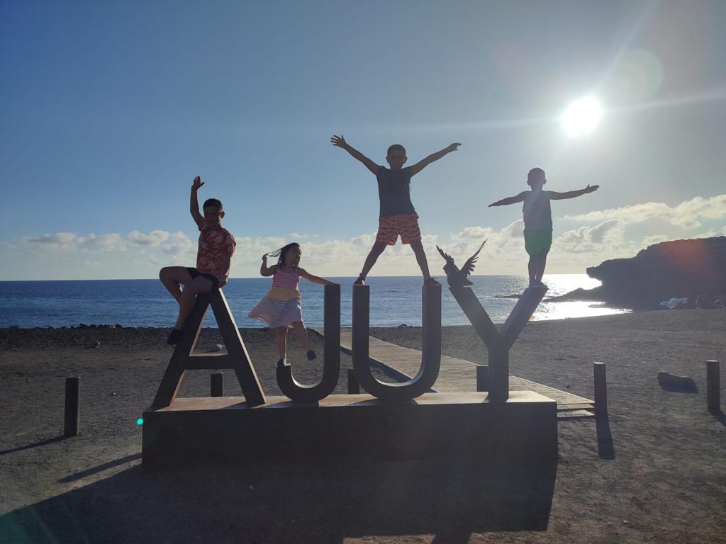 Cuatro niños subidos en las letras de Ajuy en la puesta de sol. Una de las playas más paradisiacas de Fuerteventura