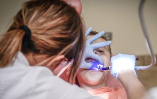 Una dentista le limpia la dentadura a un niño. Una sonrisa sana y protegida. Seguro dental para todas las edades.