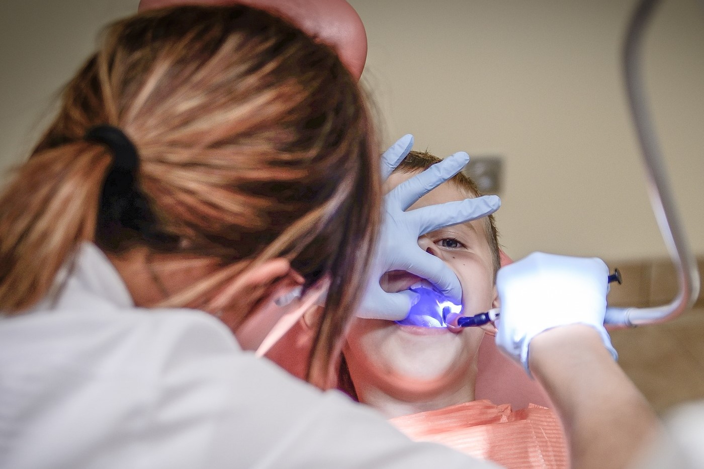 Una dentista le limpia la dentadura a un niño. Una sonrisa sana y protegida. Seguro dental para todas las edades.