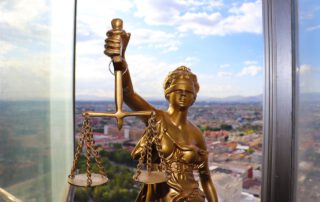 Primer plano de la estatua de la justicia y de fondo la ciudad de Cuenca, España. En Segur Torralba te podemos ofrecer un seguro de protección jurídica para automóvil por tan solo 16,26€ al año.