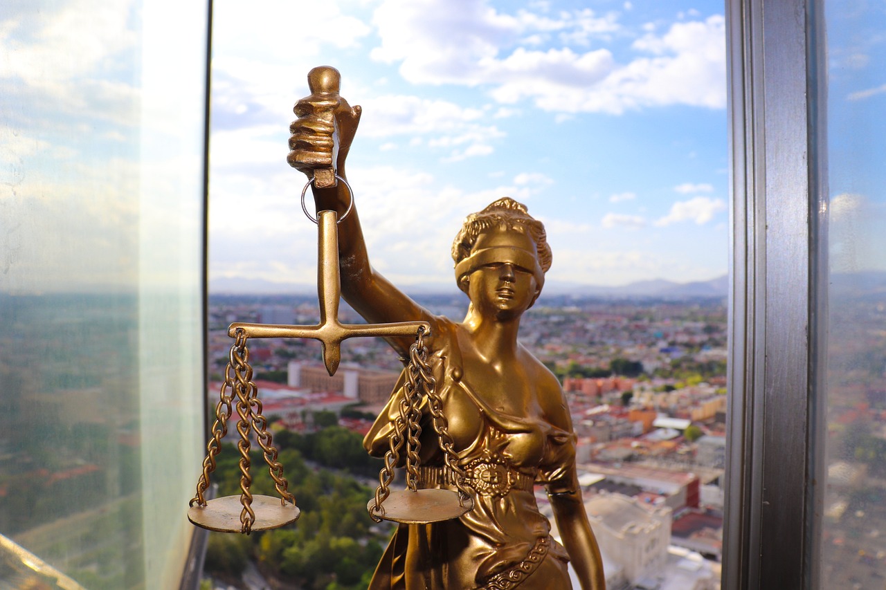Primer plano de la estatua de la justicia y de fondo la ciudad de Cuenca, España. En Segur Torralba te podemos ofrecer un seguro de Protección Jurídica para automóvil por tan solo 16,26€ al año.