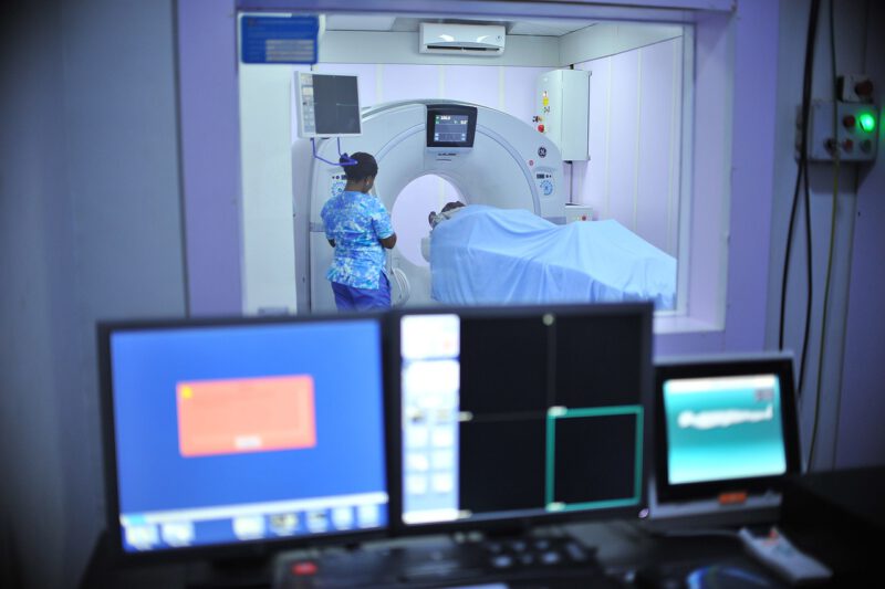 Una enfermera supervisa la entrada de un paciente en una máquina de resonancia magnética. Las claves del seguro de salud: acceso a atención médica de calidad, reduciendo la carga financiera y las listas de espera interminables de la seguridad social. 