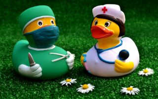 Dos juguetes tipo pollito amarillo de bañera, uno es una enfermera y el otro un médico. Los beneficios del seguro de salud. ¡Adiós lista de espera de la Seguridad Social!