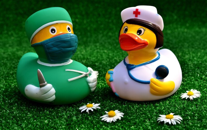 Dos juguetes tipo pollito amarillo de bañera, uno es una enfermera y el otro un médico. Los beneficios del seguro de salud. ¡Adiós lista de espera de la Seguridad Social!