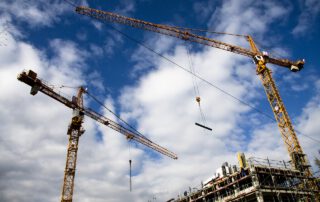 Una grúas de obra desplazando materiales de construcción en una obra. La importancia del seguro de Responsabilidad Civil