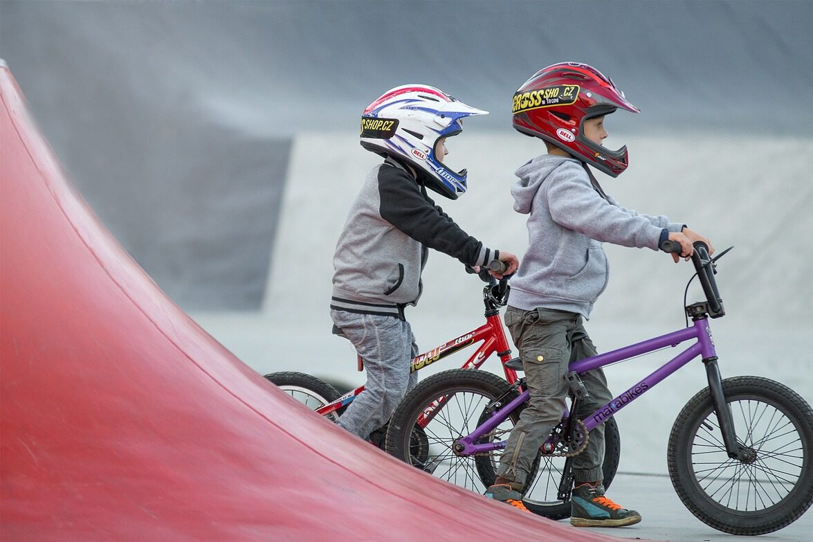 Niños practicando mountain bike en actividad deportiva extraescolar con casco de seguridad.