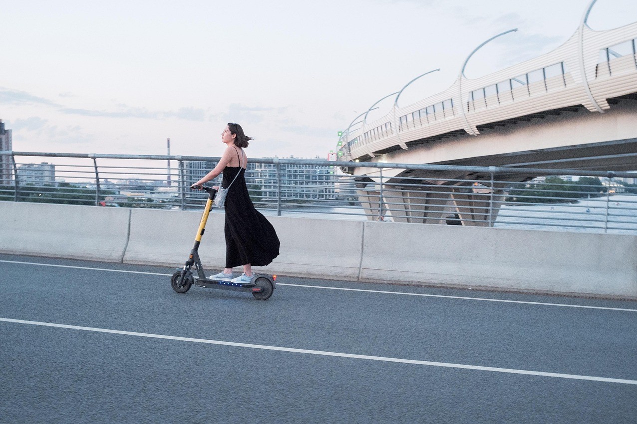 Mujer circulando en patinete eléctrico por una vía urbana en Valencia. Nueva ley de seguro obligatorio para patinetes eléctricos.