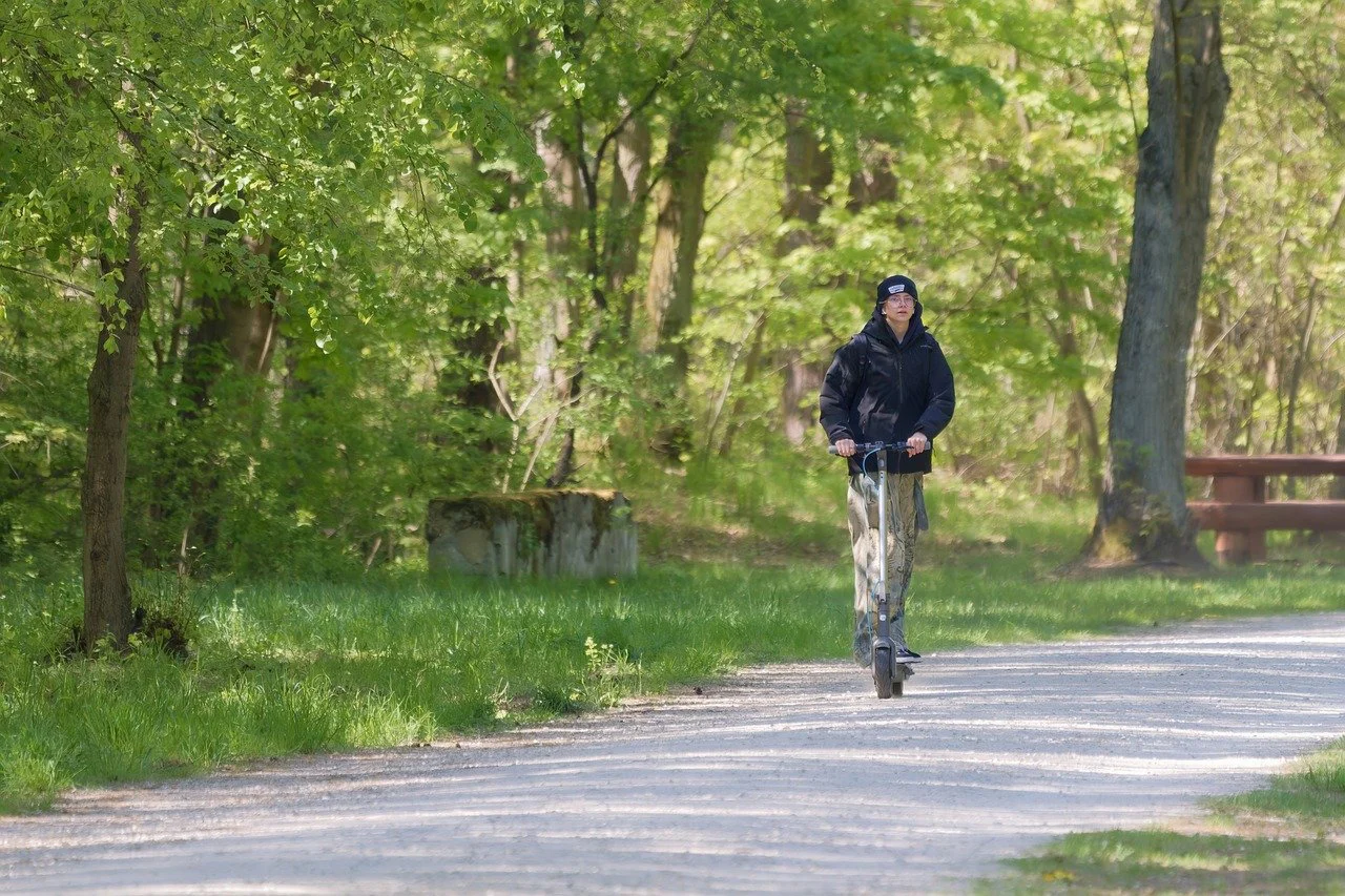 Seguro para movilidad personal Persona circulando en patinete eléctrico por un parque, ejemplo de movilidad personal asegurada.