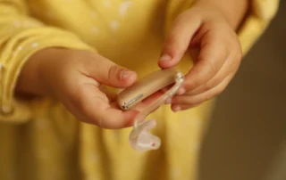 Manos de un niño sosteniendo un audífono retroauricular, dispositivo que puede protegerse con el Seguro de Audífonos de Segur Torralba.