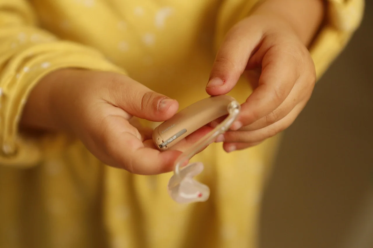 Manos de un niño sosteniendo un audífono retroauricular, dispositivo que puede protegerse con el Seguro de Audífonos de Segur Torralba.