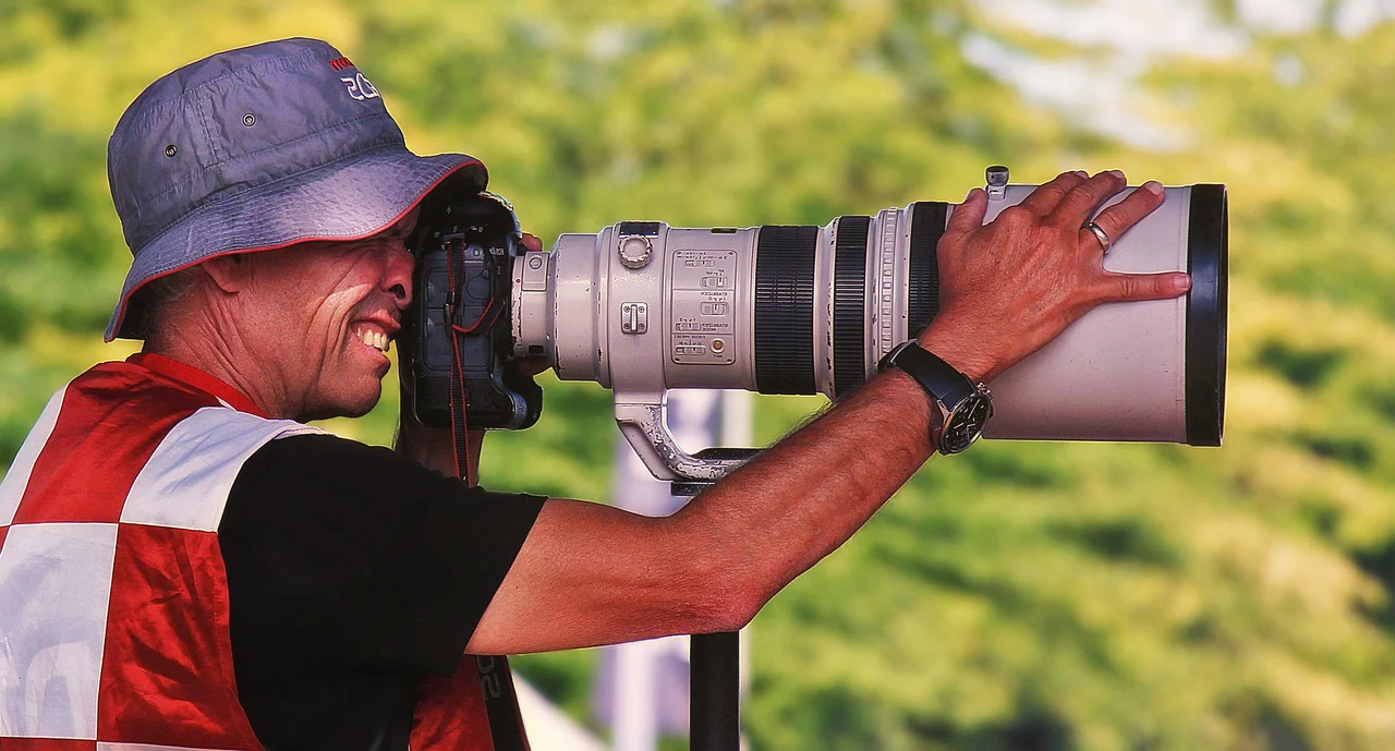 Fotógrafo utilizando una cámara profesional con teleobjetivo, equipo que puede protegerse con el Seguro de Cámaras de Segur Torralba.